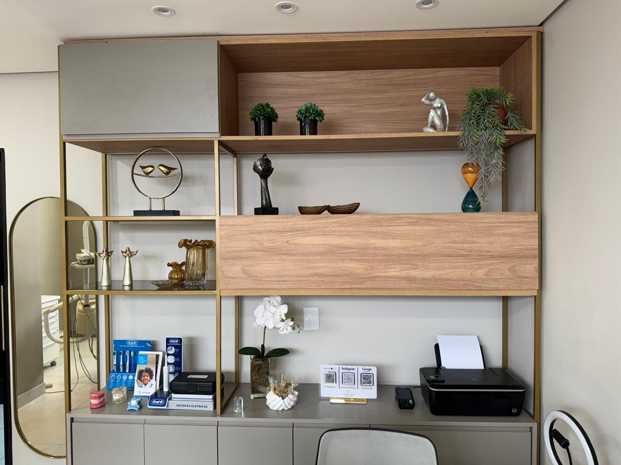 Estante do consultório com plantas, objetos decorativos e iluminação em tons quentes